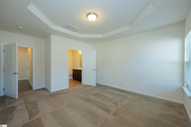 unfurnished bedroom featuring a raised ceiling, light carpet, baseboards, and ornamental molding