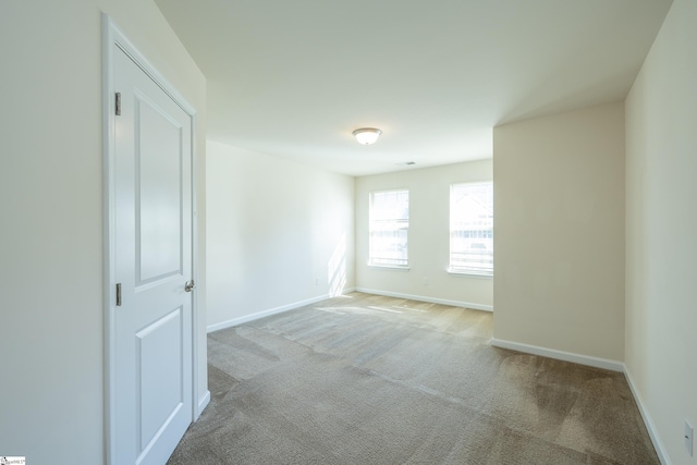 empty room featuring light carpet and baseboards