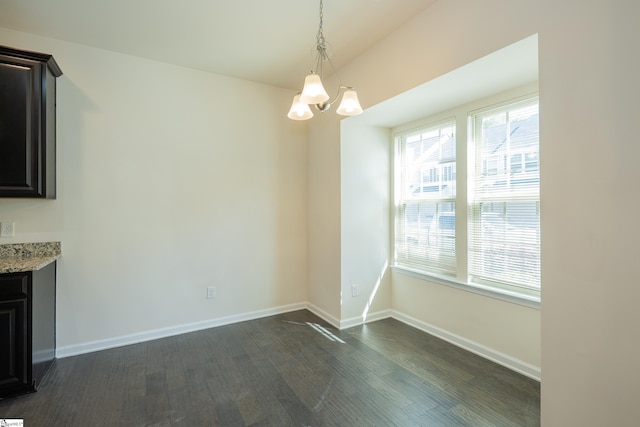 unfurnished dining area featuring baseboards, dark wood-style floors, and an inviting chandelier