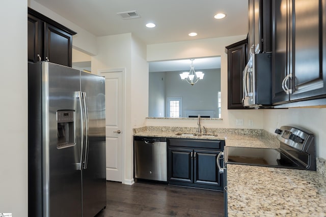 kitchen with dark wood-style floors, stainless steel appliances, visible vents, a sink, and a notable chandelier