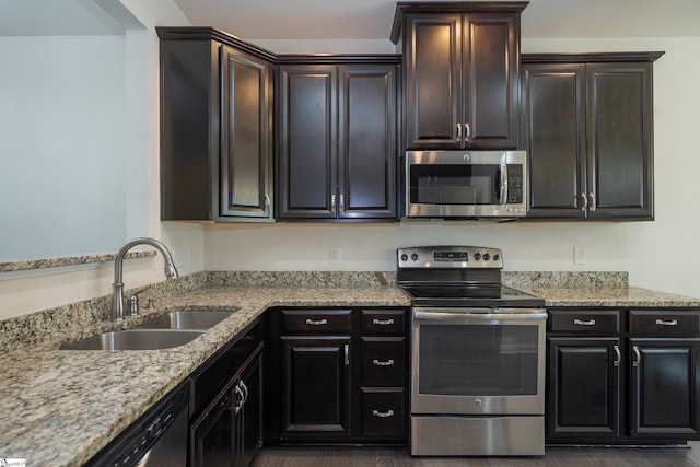 kitchen featuring light stone countertops, stainless steel appliances, dark wood-type flooring, and a sink