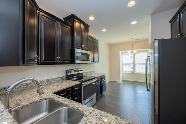 kitchen with recessed lighting, dark wood finished floors, stainless steel appliances, a sink, and light stone countertops