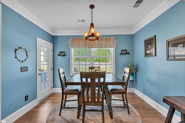 dining area featuring wood finished floors, visible vents, and an inviting chandelier