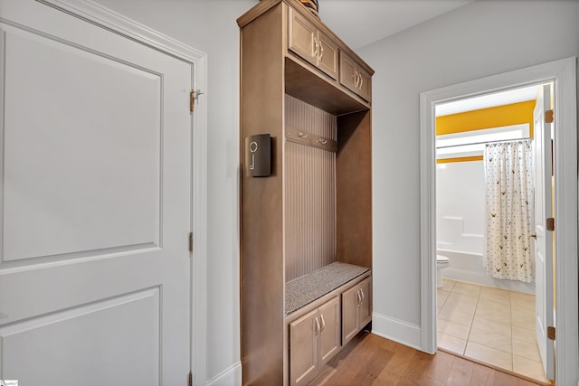 mudroom featuring light wood finished floors and baseboards