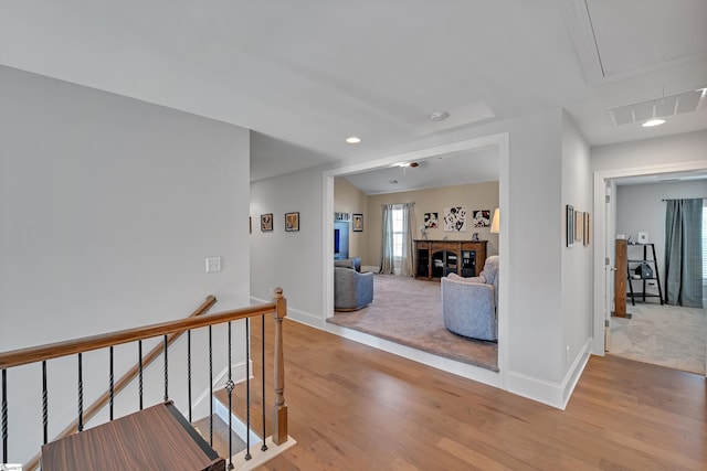 corridor featuring an upstairs landing, attic access, visible vents, and light wood-style floors