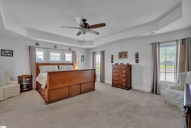bedroom with a tray ceiling, carpet floors, visible vents, and multiple windows