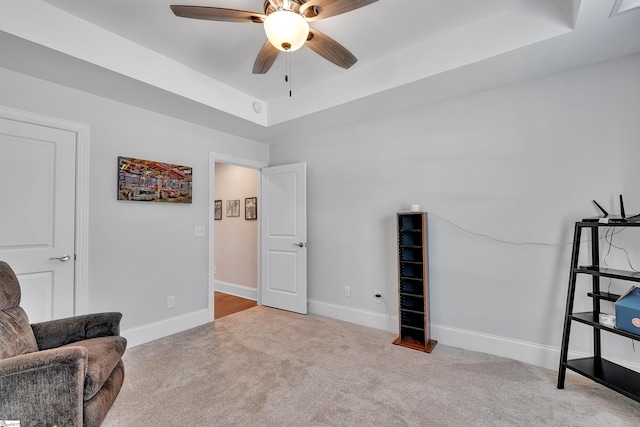 sitting room featuring ceiling fan, baseboards, carpet flooring, and a raised ceiling