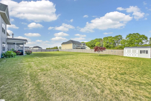 view of yard with a fenced backyard, a storage unit, and an outbuilding