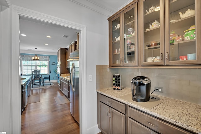 bar with backsplash, dark wood-style flooring, crown molding, and stainless steel refrigerator