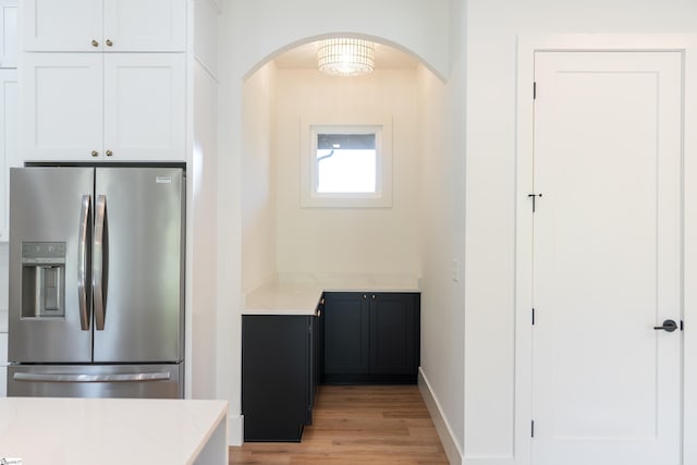545 E Airport Rd, Greer, SC 29651 - kitchen featuring arched walkways, stainless steel fridge with ice dispenser, light wood-style flooring, white cabinets, and baseboards