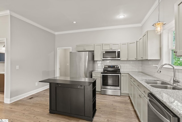 kitchen featuring stainless steel appliances, a sink, tasteful backsplash, light stone counters, and ornamental molding
