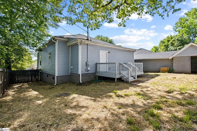 back of property with a wooden deck, fence, and crawl space