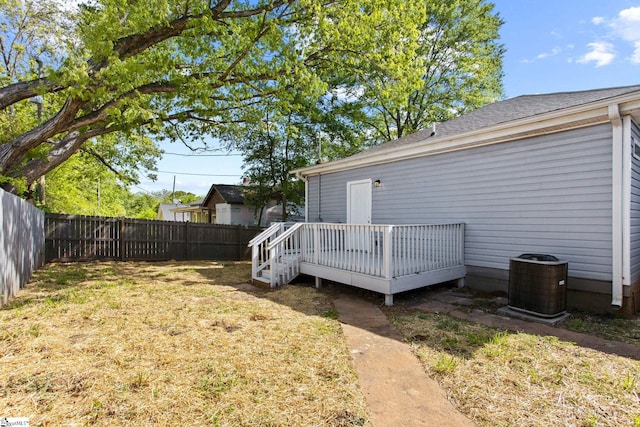 view of yard with a wooden deck, a fenced backyard, and central AC unit