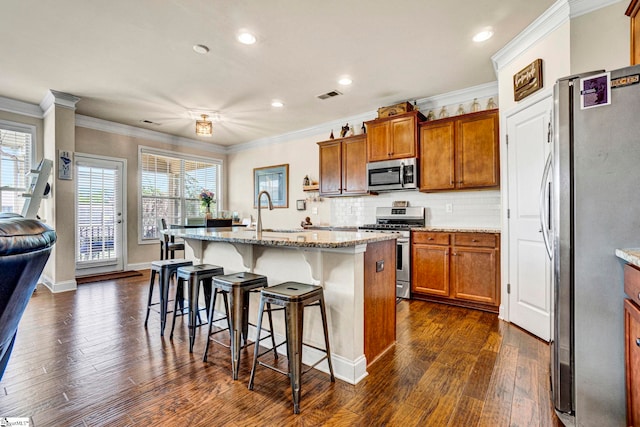kitchen with dark wood finished floors, brown cabinetry, visible vents, and stainless steel appliances