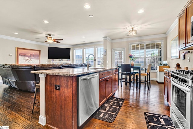 kitchen featuring ornamental molding, open floor plan, stainless steel appliances, and a sink