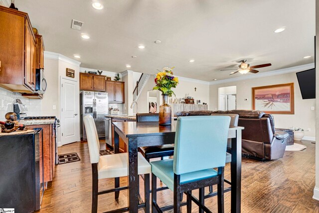 dining room with recessed lighting, wood finished floors, visible vents, a ceiling fan, and crown molding