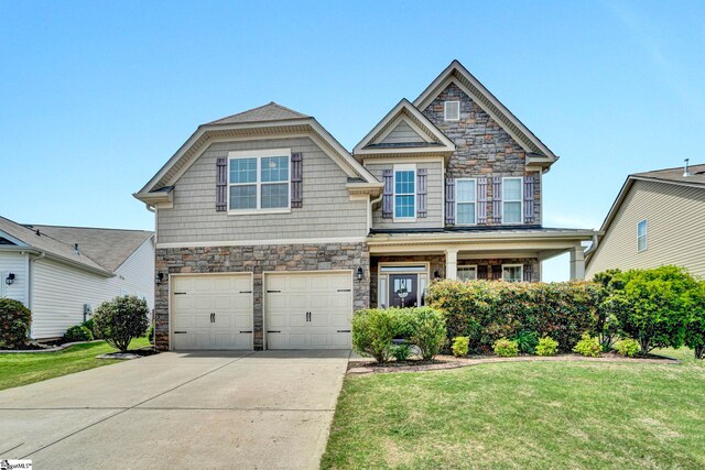 craftsman house featuring a garage, stone siding, a front yard, and concrete driveway