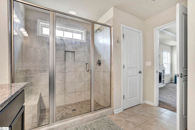 bathroom with baseboards, tile patterned flooring, a shower stall, and a healthy amount of sunlight