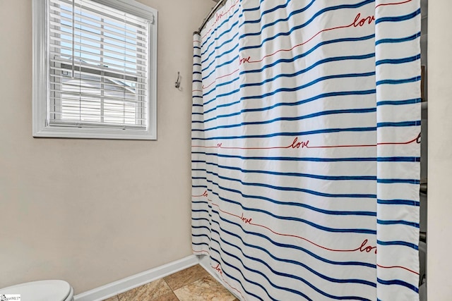 bathroom with toilet, baseboards, and a shower with curtain
