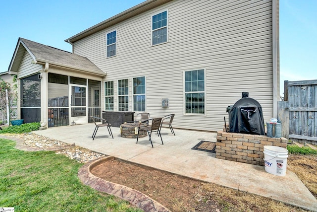 rear view of house with a fire pit, a sunroom, fence, and a patio area