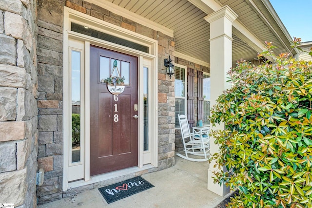 property entrance featuring stone siding and covered porch