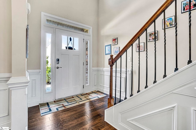 entrance foyer featuring wainscoting, hardwood / wood-style flooring, a decorative wall, and stairway