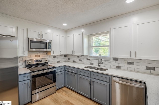 kitchen featuring stainless steel appliances, light countertops, a sink, and gray cabinets