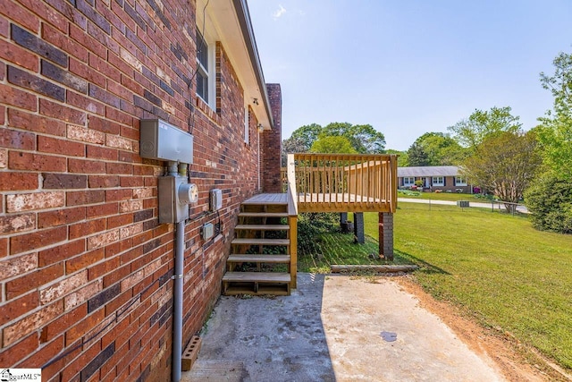 view of property exterior with a lawn, brick siding, and a deck
