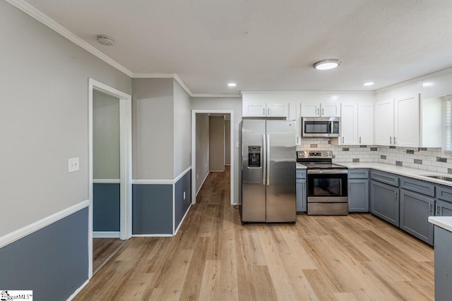 kitchen featuring decorative backsplash, light wood-type flooring, gray cabinets, light countertops, and appliances with stainless steel finishes