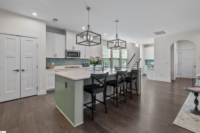 kitchen featuring stainless steel microwave, dark wood-type flooring, visible vents, and light countertops