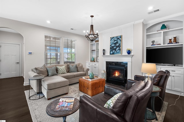 living area with dark wood finished floors, visible vents, arched walkways, a glass covered fireplace, and built in shelves