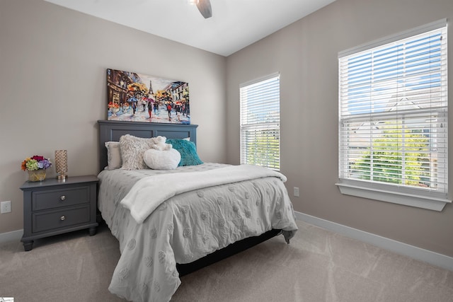 bedroom with a ceiling fan, baseboards, and light carpet