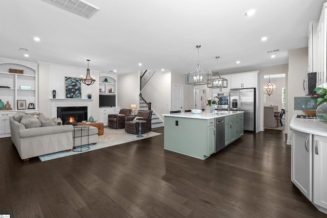 kitchen featuring open floor plan, a glass covered fireplace, a notable chandelier, and appliances with stainless steel finishes