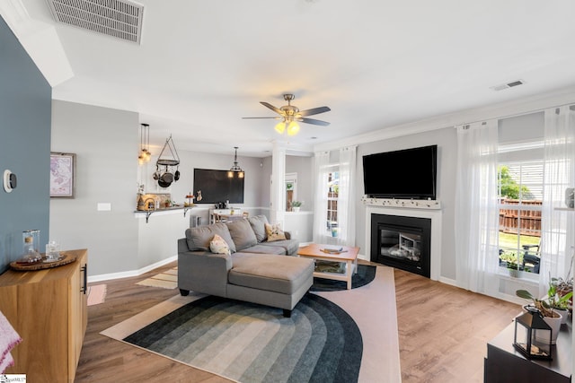 living area featuring light wood-style flooring, visible vents, a ceiling fan, and baseboards