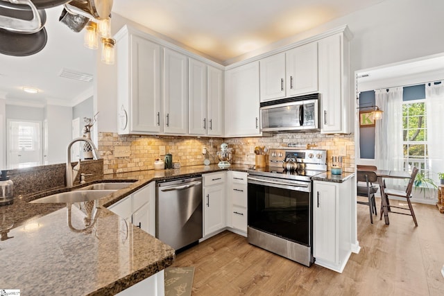 kitchen with white cabinets, a sink, dark stone countertops, visible vents, and appliances with stainless steel finishes
