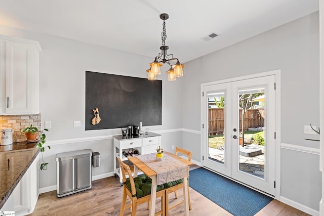 dining room featuring light wood finished floors, visible vents, french doors, baseboards, and a notable chandelier
