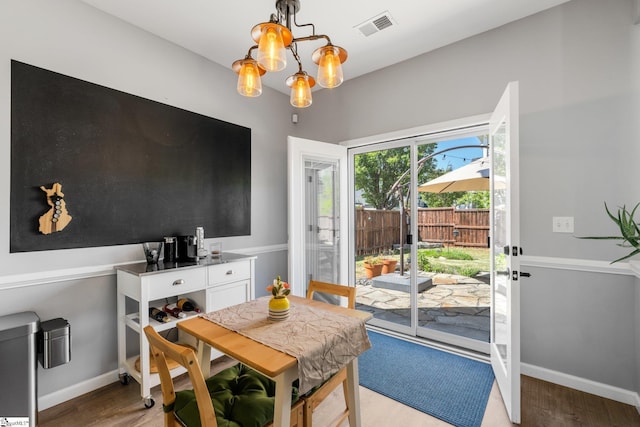 dining area with light wood-type flooring, visible vents, baseboards, and an inviting chandelier