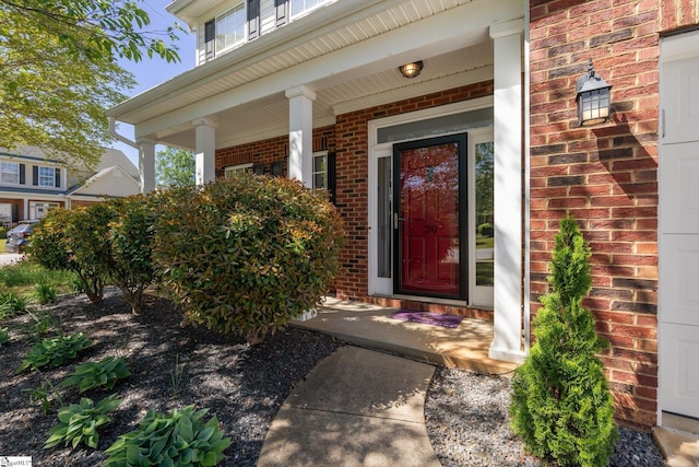 entrance to property featuring brick siding and covered porch