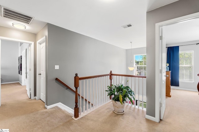 corridor featuring visible vents, carpet flooring, baseboards, and an upstairs landing