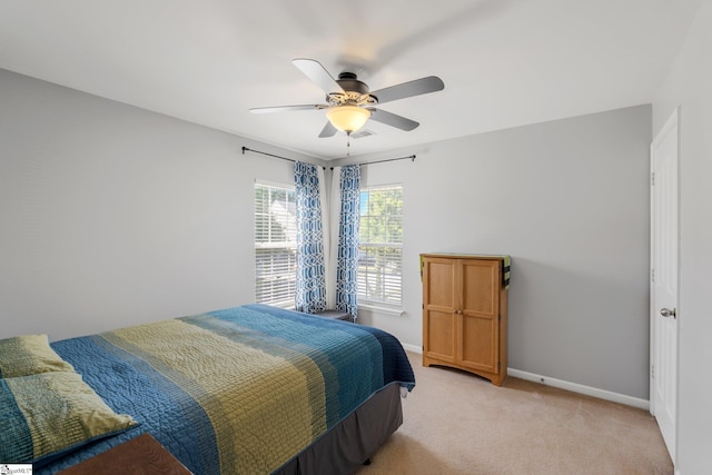 bedroom featuring light carpet, a ceiling fan, and baseboards