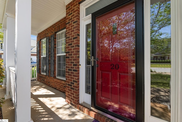 property entrance with brick siding and a porch