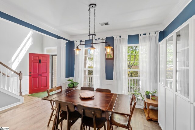 dining area featuring light wood-type flooring, visible vents, stairs, and ornamental molding