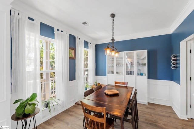 dining area featuring crown molding, wood finished floors, and a wainscoted wall