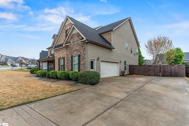 view of property exterior with concrete driveway, a lawn, a shingled roof, an attached garage, and fence