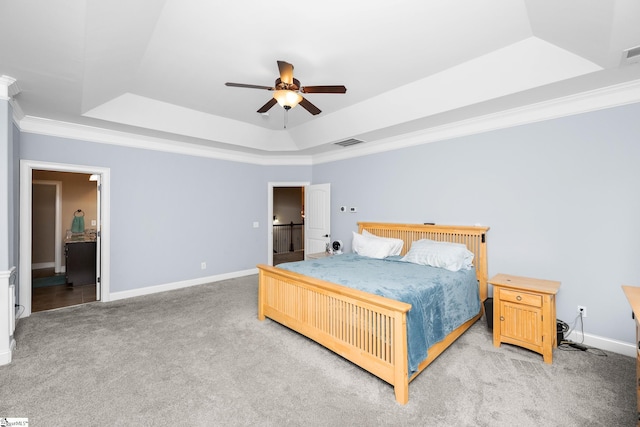 bedroom with crown molding, light carpet, a tray ceiling, baseboards, and visible vents