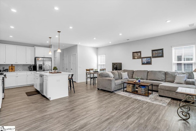 living area featuring recessed lighting, light wood-type flooring, visible vents, and baseboards
