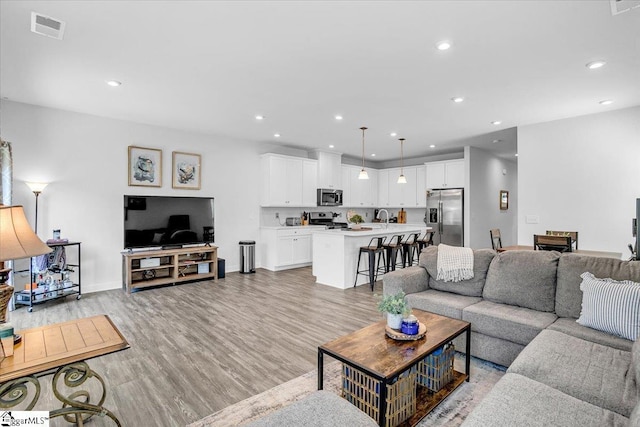 living area with baseboards, recessed lighting, visible vents, and light wood-style flooring