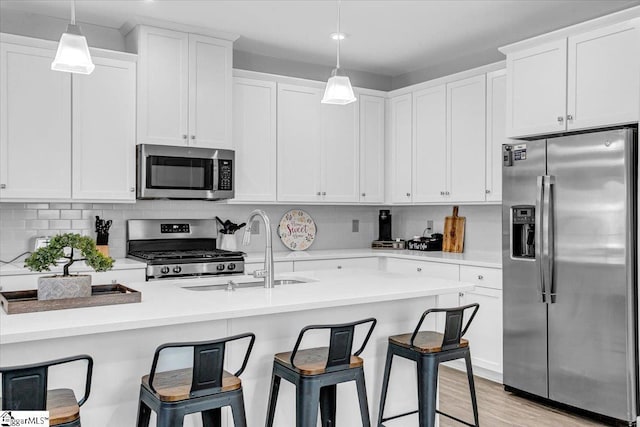 kitchen featuring a breakfast bar, white cabinetry, stainless steel appliances, and a sink