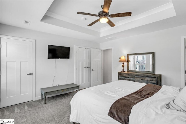bedroom featuring a raised ceiling, visible vents, a closet, carpet flooring, and ceiling fan