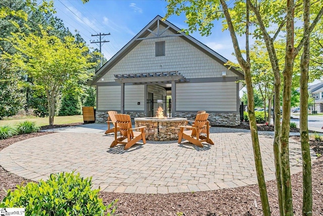 rear view of house featuring a fire pit, stone siding, a pergola, and a patio area